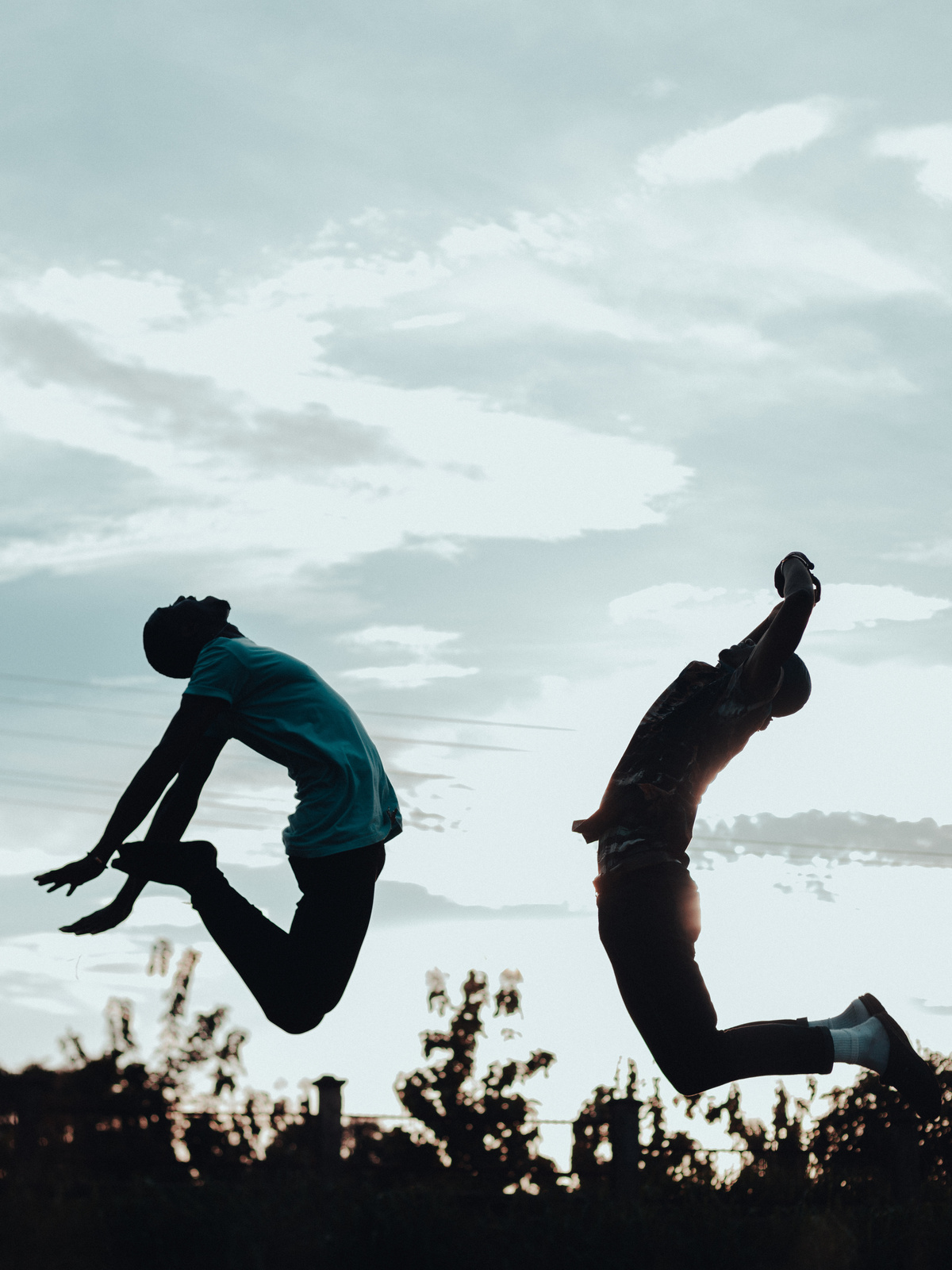 Silhouette of Two Men Jumping Outdoors